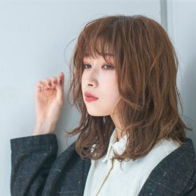 髪をつまむ明るいブラウンヘアの女性の写真