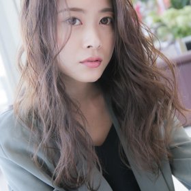 真ん中分けのウェーブのかかったロングヘアの女性の写真