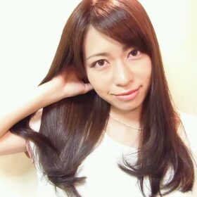 髪をかきあげるロングヘアの女性の写真