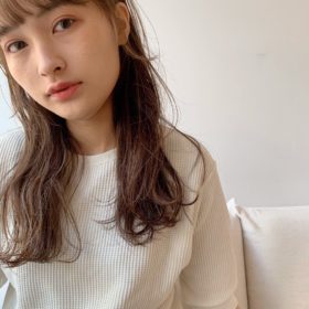 くすんだ茶色のロングヘアでゆるやかパーマをかけた女性の写真