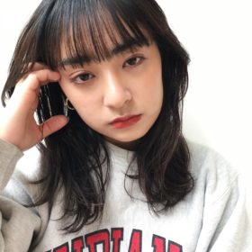 前髪がそろった黒髪ロングの耳に書き上げるしぐさの女性の写真