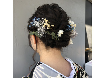 黒髪に青いヘアアクセサリーが映えるアップスタイルの写真