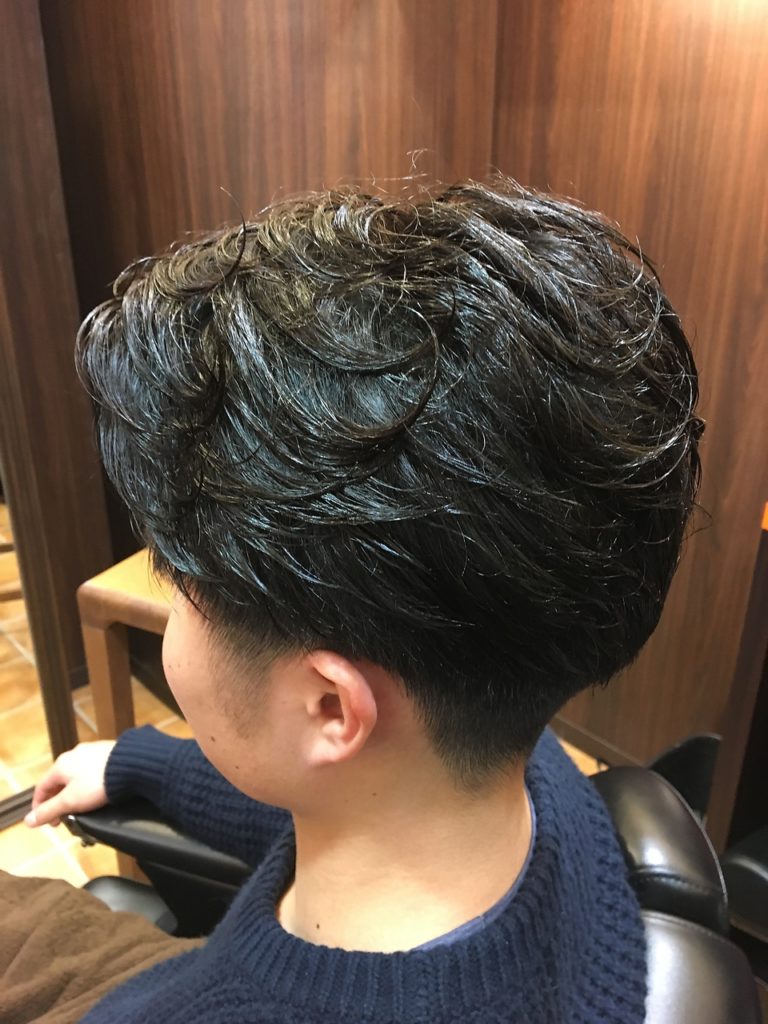 黒髪ゆるやかパーマヘアの男性のバックスタイル写真
