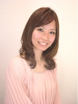 ブラウンカラーの内巻きロングヘアのピンク色のトップスを着た女性の写真