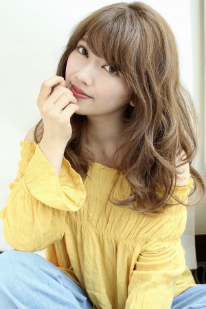 顎に手を添えるロングパーマヘアの女性の写真