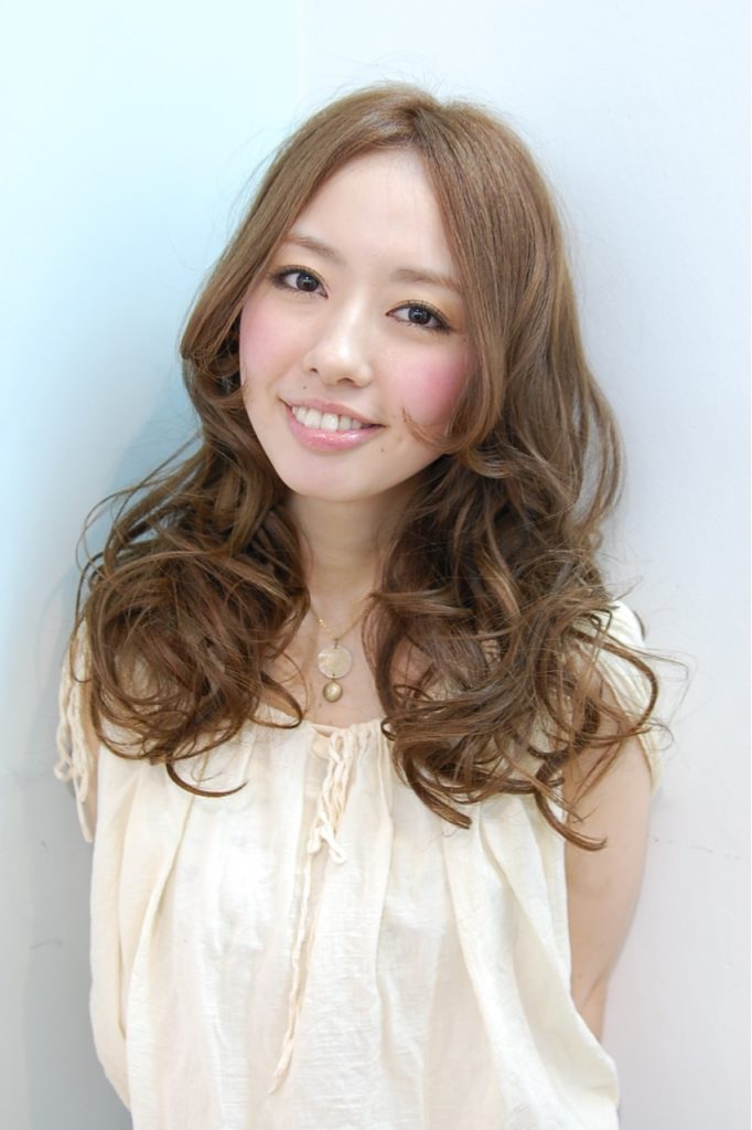 ベージュカラーの巻き髪ロングヘアの女性の写真