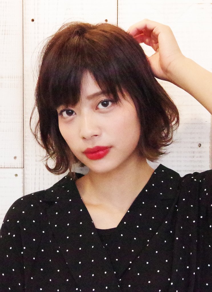 ふんわりとしたボブスタイルの髪をかきあげる女性の写真