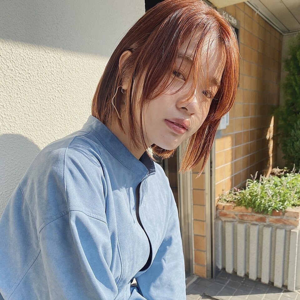 オレンジカラーのボブスタイルの女性の写真
