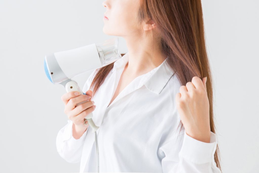 ドライヤーで髪を乾かす女性の写真