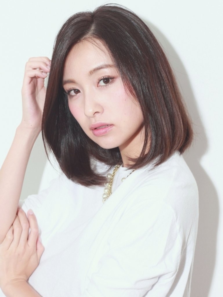 髪をかきあげる黒髪ミディアムヘアの女性の写真