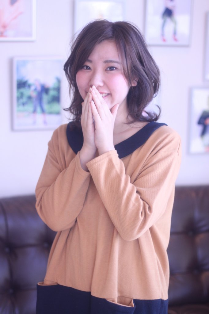 顔の前で手を合わせる外はねボブスタイルの女性の写真
