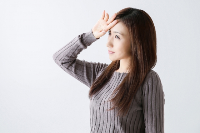 額に手を当てる女性の写真