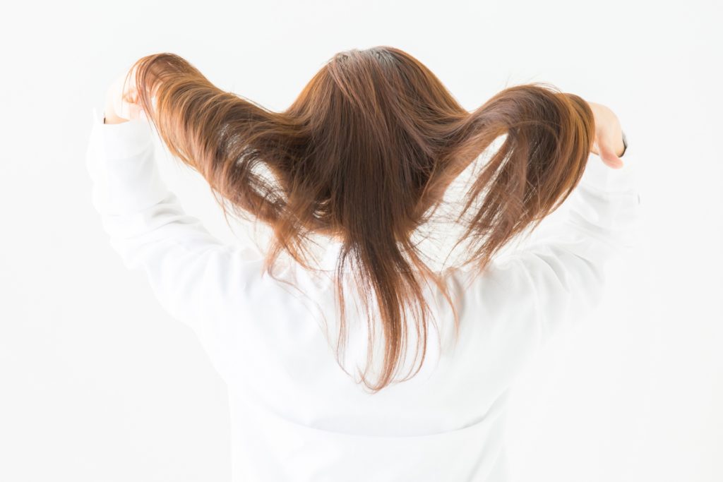 髪をかき上げる女性の写真