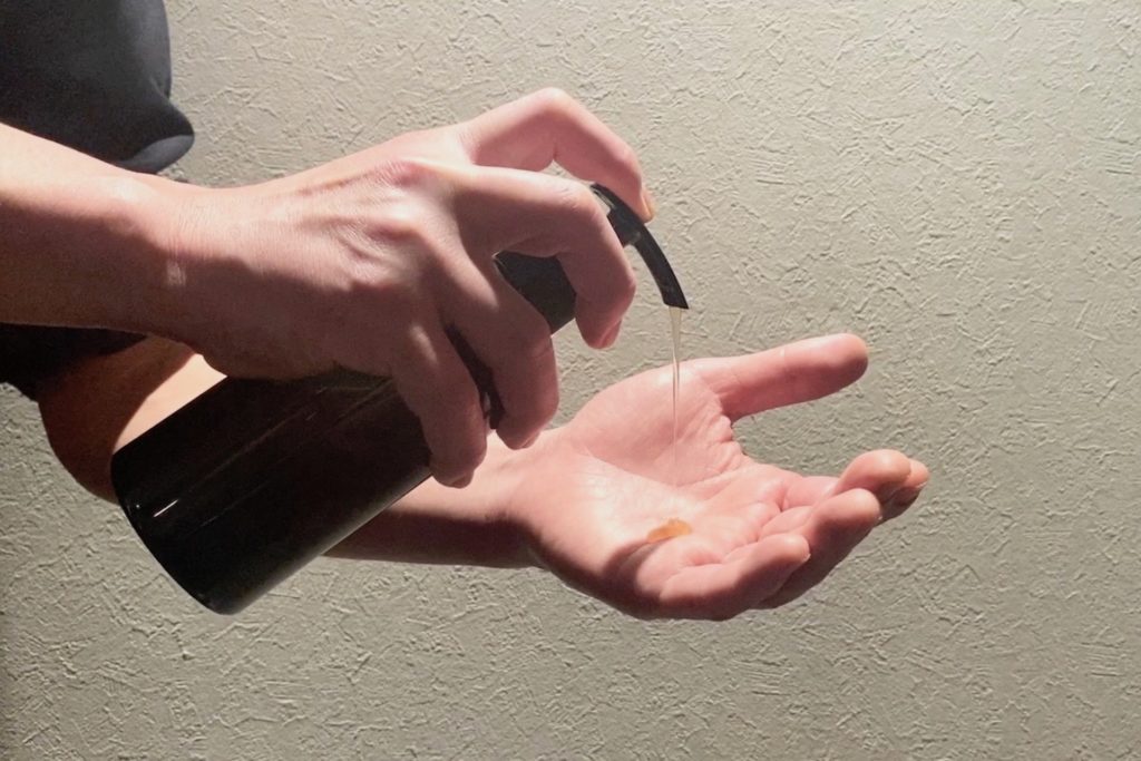シャンプーボトルと手の写真