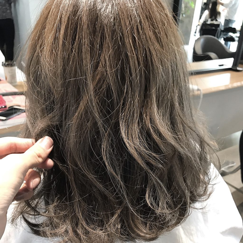 カラーリングする前にブリーチをする女性の後ろ姿