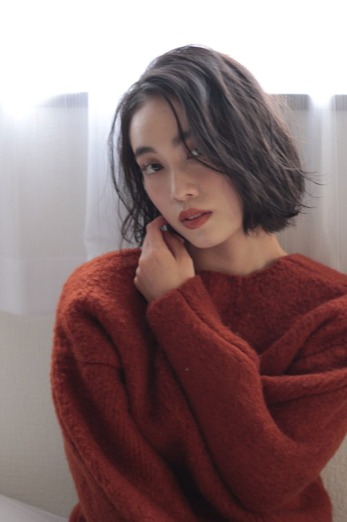 手を顔に添えたボブヘアの女性の写真