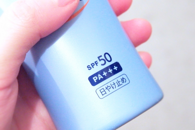 SPF50の文字が書かれた日焼け止めを持つ女性の手