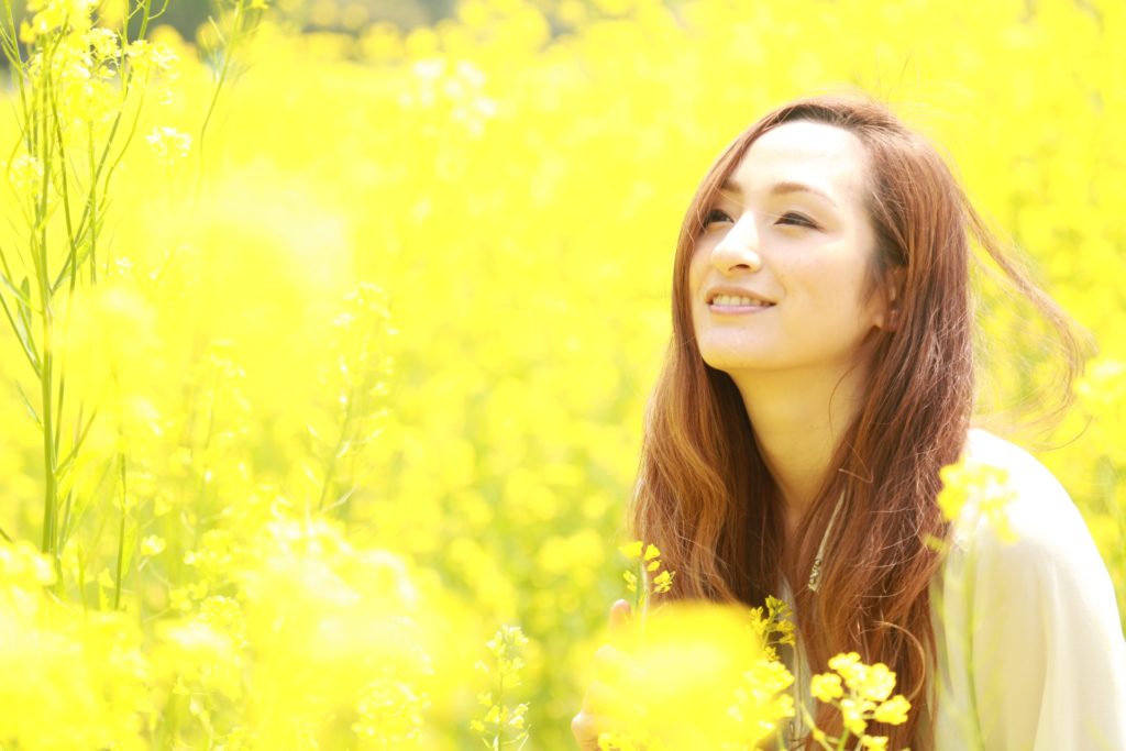 お花畑で微笑むナチュラルウェーブスタイルの綺麗な女性