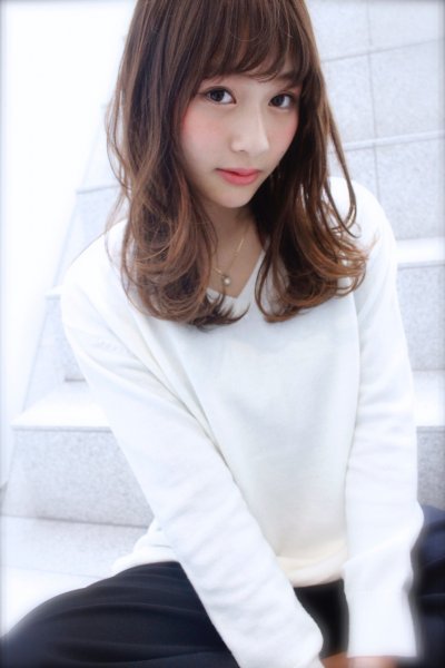 ナチュラル的なストレートヘアの女性が真っ白い薄手のセーターを着ている様子