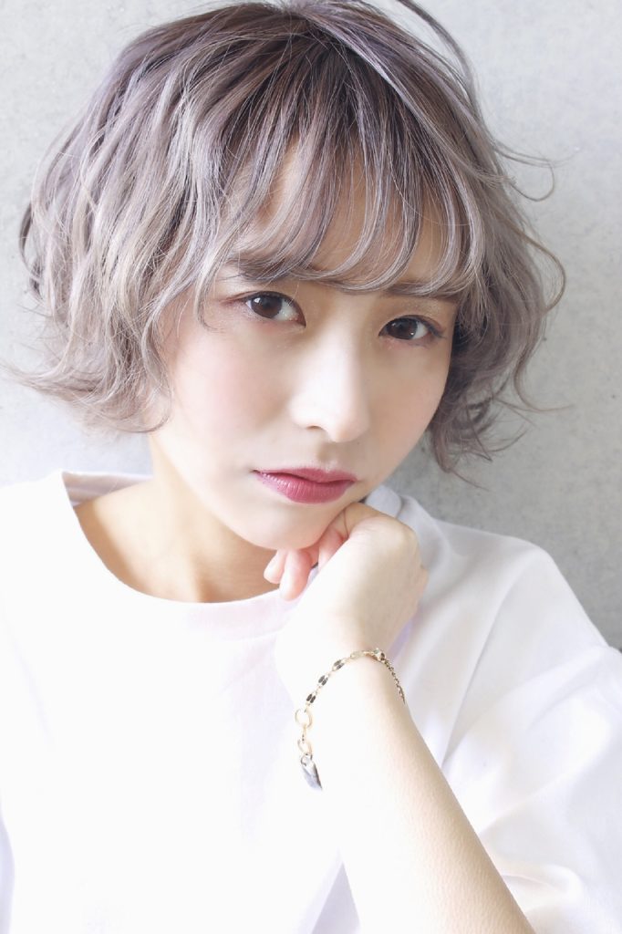 白いオシャレスウェットを着たシルバーカラーのショートウェーブヘア女子