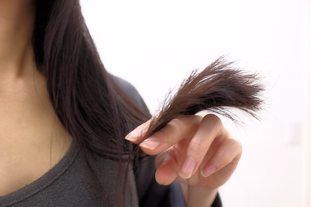 キューティクルが傷んだ髪を悲しそうに眺める様子
