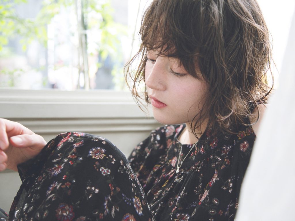 柄のワンピースを着たナチュラルヘアのアンニュイな女性