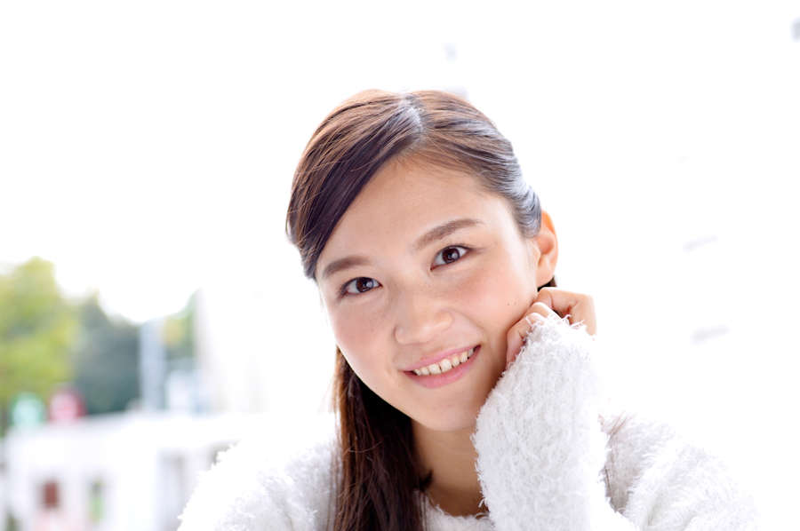 白いセーターを着た濃いめのブラウンカラーのオシャレ女子
