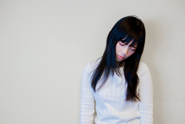 ナチュラルメイクの女性が元気なくうつむく様子