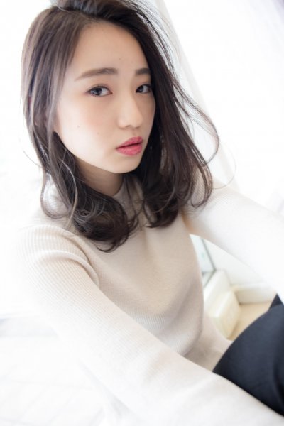 白いカットソーを着たロングボブの女性が上目遣いで見る様子の写真