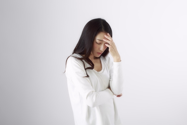 女性が体調不良で頭痛に悩む様子