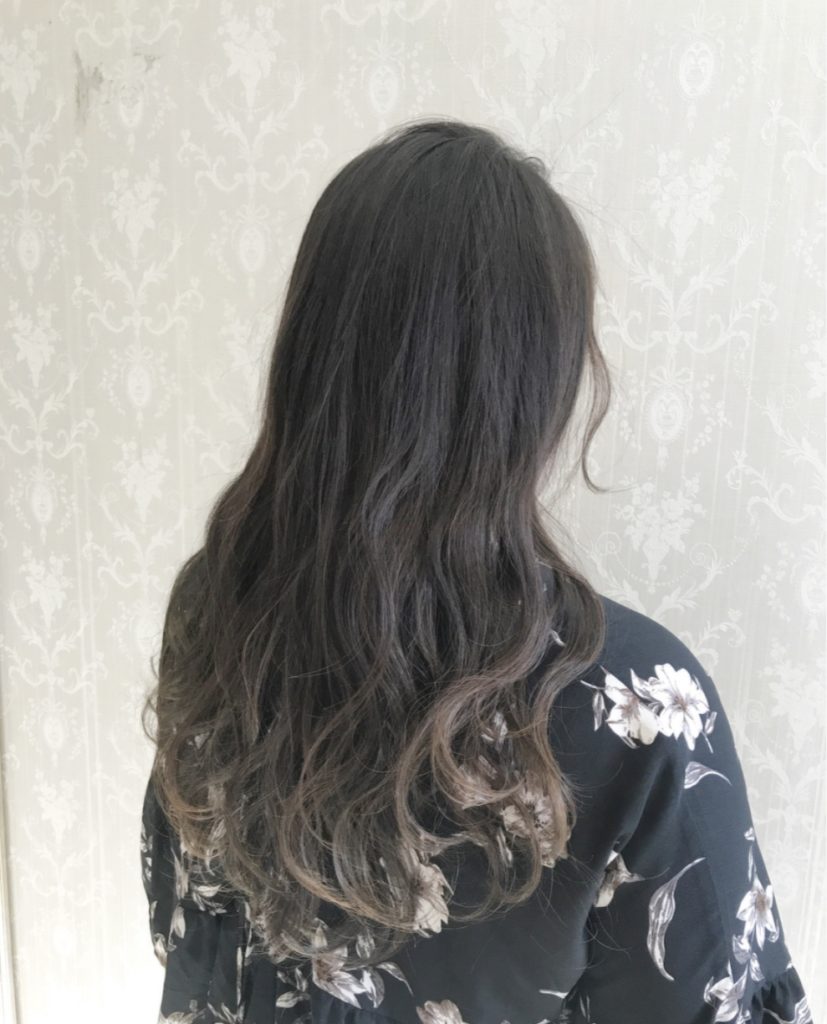 髪をグラデーションに仕上げ素敵なウェーブヘアの女性後ろ姿