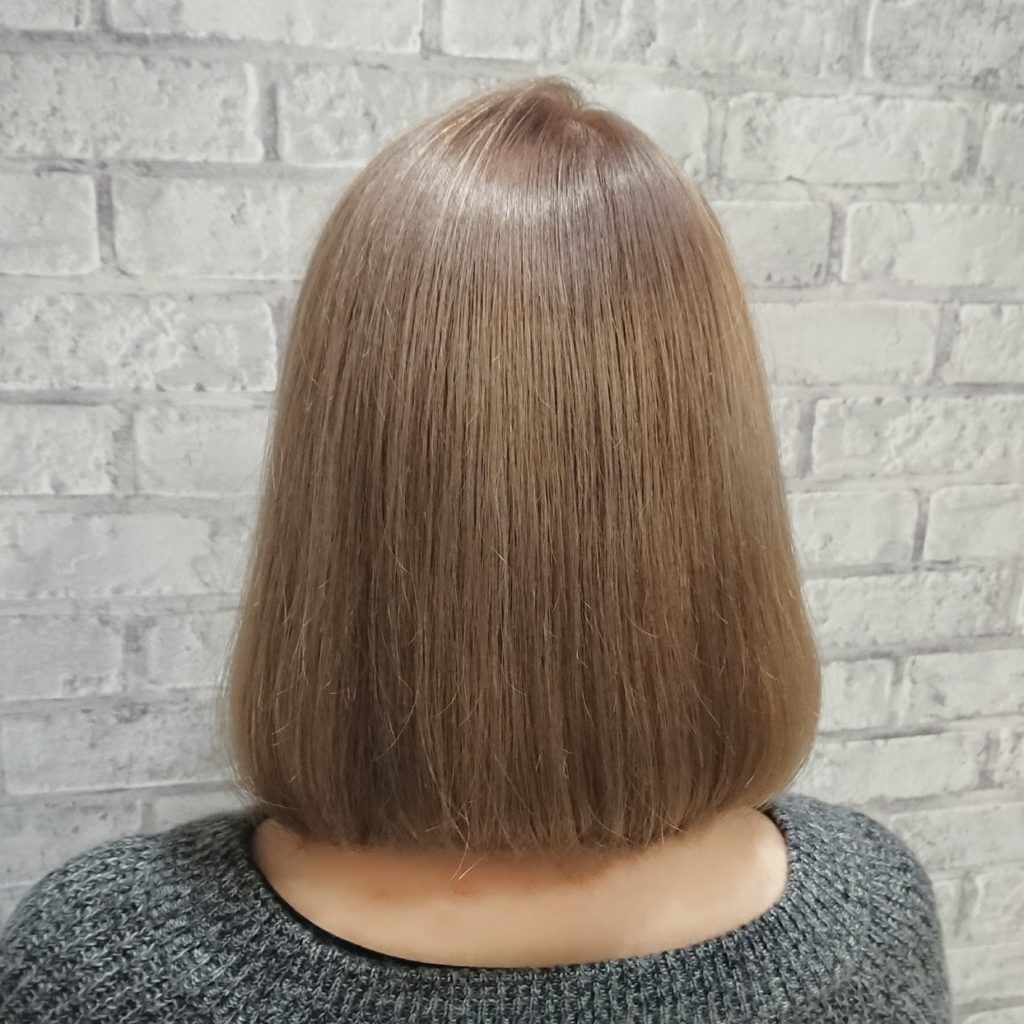髪の長さはミドルレンジ。ベージュ系のブリーチをした女性の後姿