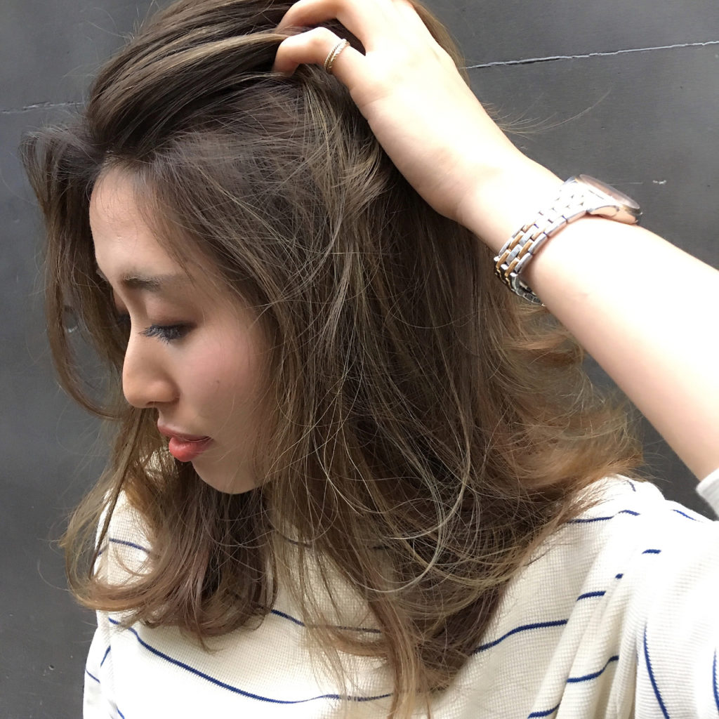 ハイライトでお洒落な女性が髪をかき上げている様子