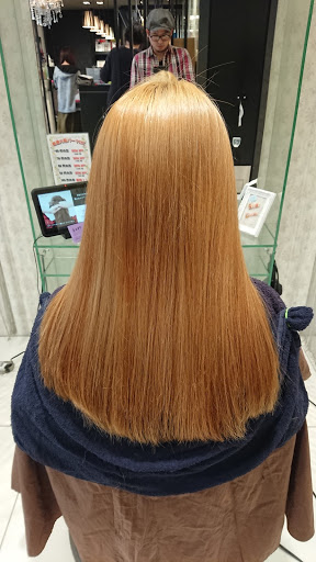 オレンジゴールド色したロングヘアの女性の後姿