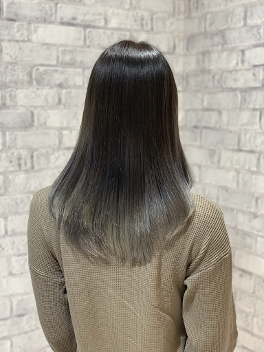 シルバー色のグラデーションカラーロングヘアの女性の髪が光り輝く様子真後ろから