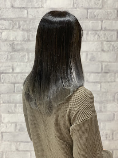 シルバー色のグラデーションカラーロングヘアの女性の髪が光り輝く様子斜め後ろから