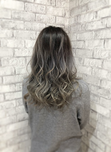 シルバー色の髪色ウェーブヘアの女性真後ろから