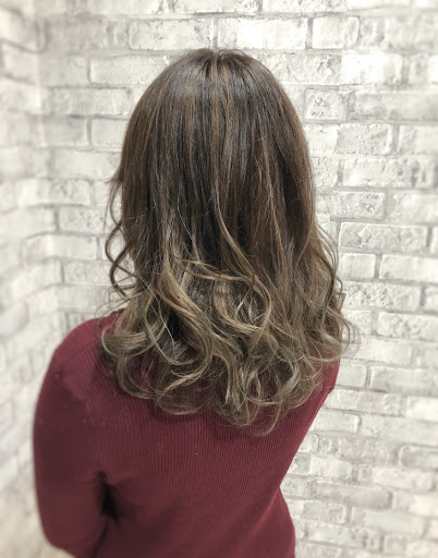シルバー色の髪色ウェーブヘアの女性斜め後ろから