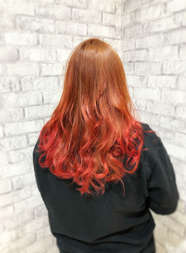 オレンジ系で全体を仕上げたロングウェーブヘアの女性後ろ姿