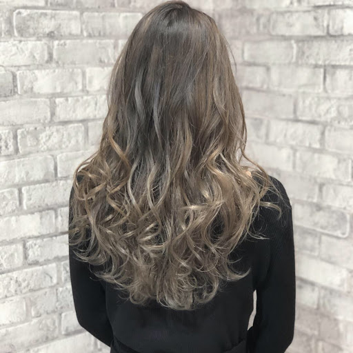 ロングヘアでウェーブが掛かった髪をミルクティーベージュ系にブリーチした様子