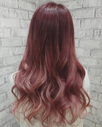 ロングヘアでウェーブが掛かった髪をピンク系にブリーチした様子