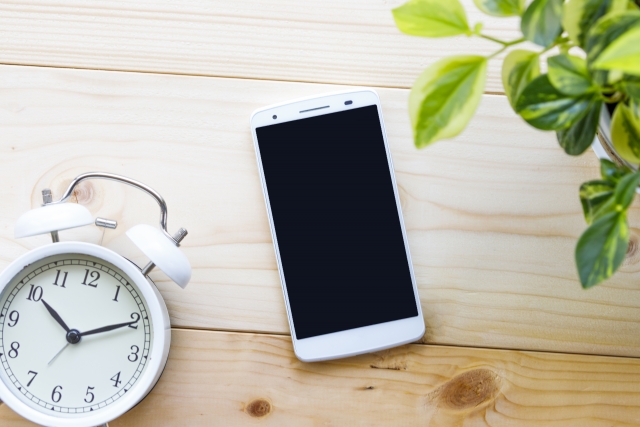 予約をする時のスマホと時計のイメージショット