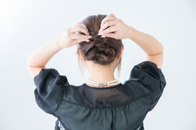 ヘアスタイルを鏡の前で直す女性