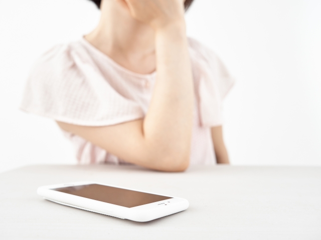 電話を一旦切って考えごとをする女性