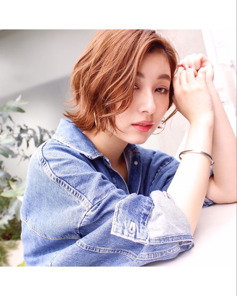 デニムのアウターを羽織った明るいブラウンショートヘア女性