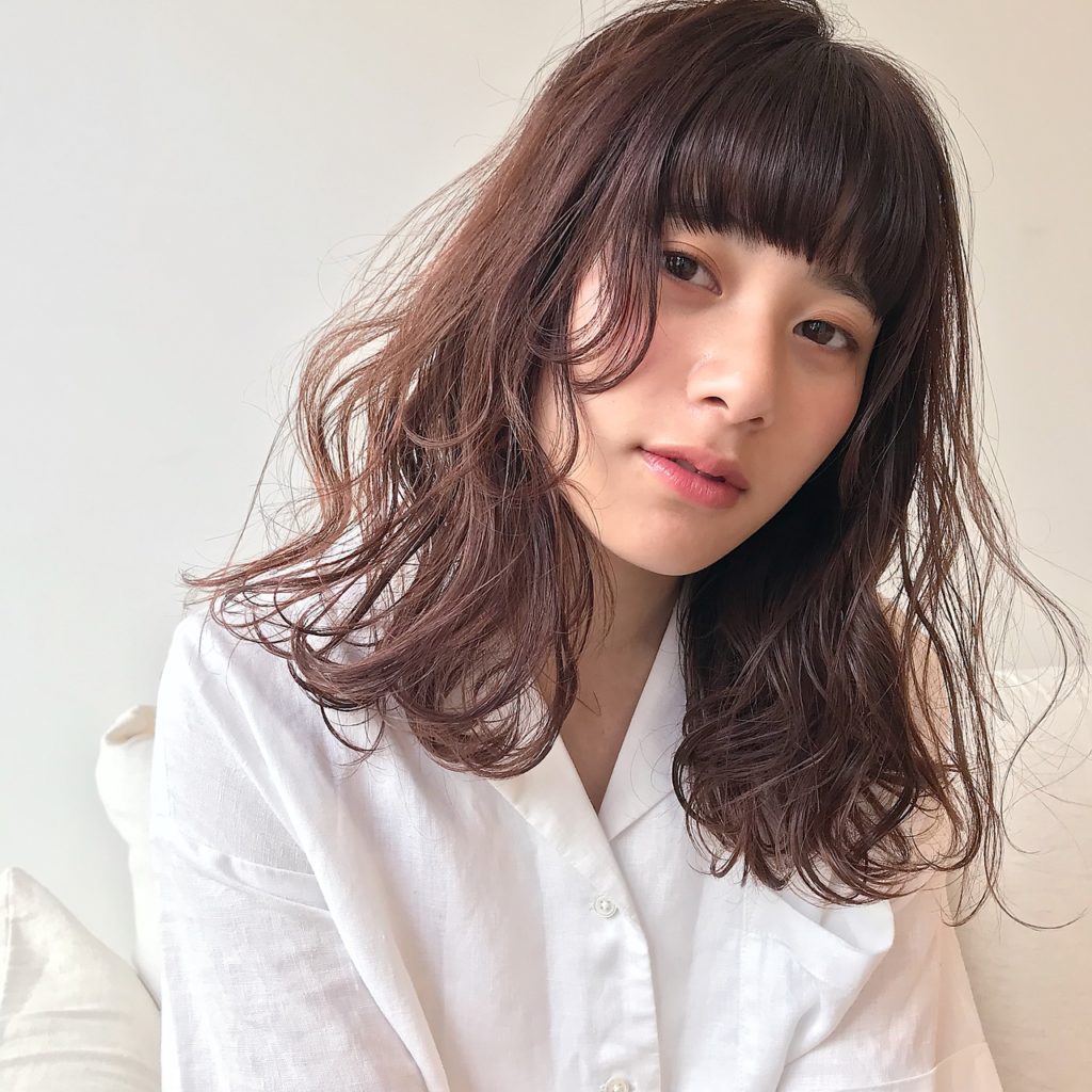 ぱっつん前髪でウェーブミディアムヘアの可愛らしい女性