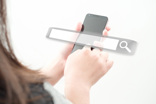 スマホでホームページを検索する女性の手