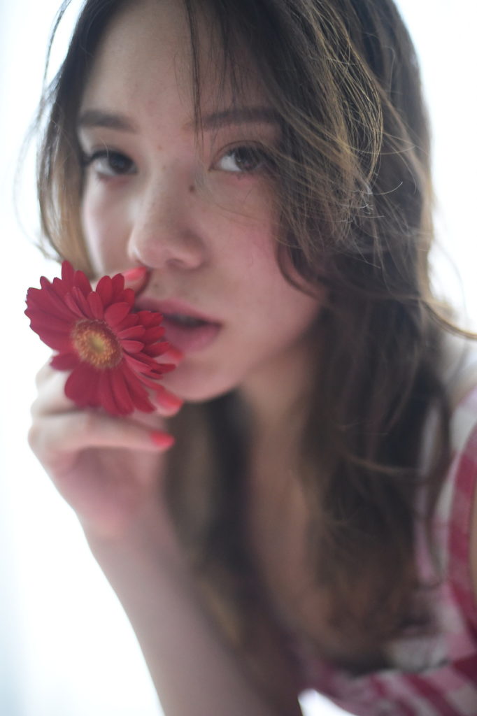 花を軽く咥えポーズをとるロングヘアのエスニック女子