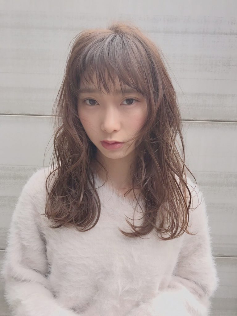寂しそうな表情でこちらを見つめるミディアムウェーブヘア女性