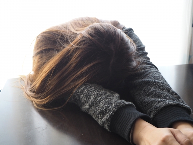 ロングヘアの女性が疲れてうつ伏せになっている様子